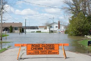 Photo shows a sign saying road closed with a flooded street in the background, Canada's top ten weather stories 2017 by David Phillips