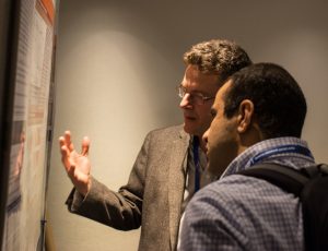 Photo shows two men looking at a scientific poster at the CMOS Congress