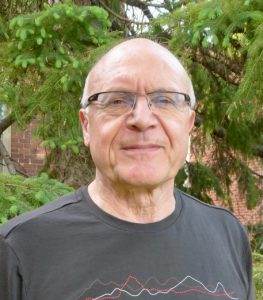 Photograph of Wayne Richardson, President of CMOS. Pictured is a man's head and shoulders. He is dressed in a t-shirt. He is in his early 60's, is balding, and is wearing glasses.