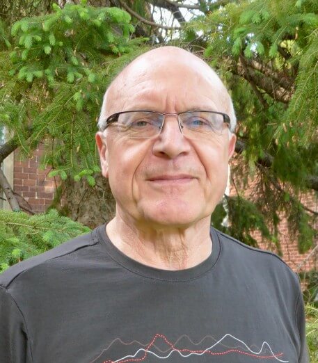 Photograph of Wayne Richardson, President of CMOS. Pictured is a man's head and shoulders. He is dressed in a t-shirt. He is in his early 60's, is balding, and is wearing glasses.