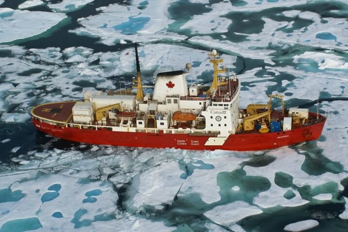Aerial view of a large research vessel moving through icy waters