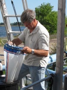 Photograph shows a caucasian man with grey hair, looking into a net.