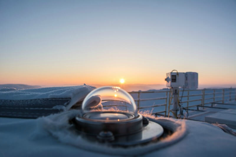 Photo shows a glass domed instrument on the rooftop at PEARL, Eureka, with the setting sun in the distance.