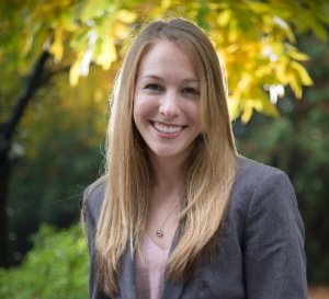 Photo shows Laura Twidle, a smiling young woman with blond hair, sitting outside with trees in the background. For Catastrophes and the INsurance industry article.