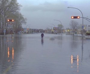 Photo of a man walking down a deserted flooded street in Montreal for the article by Bronwyn McIlroy-Young on weathercasters as climate change communicators