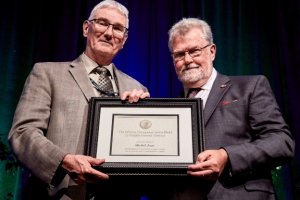 Photo showing CMOS member and Patterson medal winner Michel Jean with David Grimes of the WMO. Two men, white hair and glasses, smiling and holding a framed certificate
