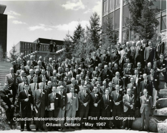 black and white photo of dozens of men in suits in front of a building at CMOS's first Congress in 1967.