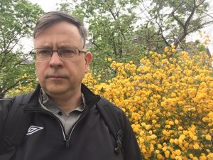 Caucasian man with glasses in front of yellow flowers