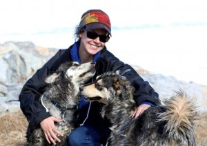smiling woman with shades and baseball cap and two large dogs