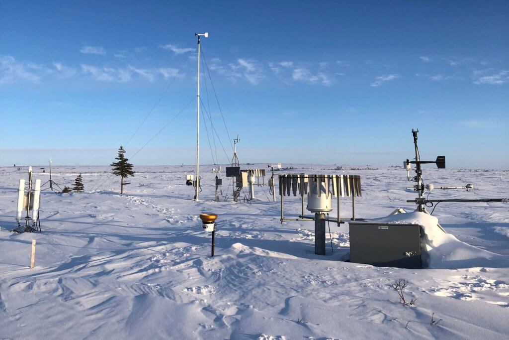 Asctic tundra landscape on a blue sky day with many metal instruments scattered throughout the landscape